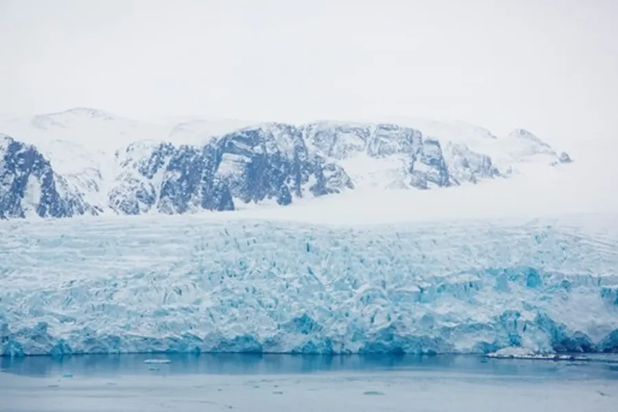Isbre som strekker seg ned mot havet, med snødekte fjell i bakgrunnen.