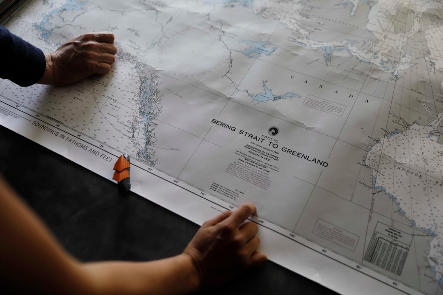 To personer holder et kart over Arktis med tittelen ‘Bering Strait to Greenland’.
