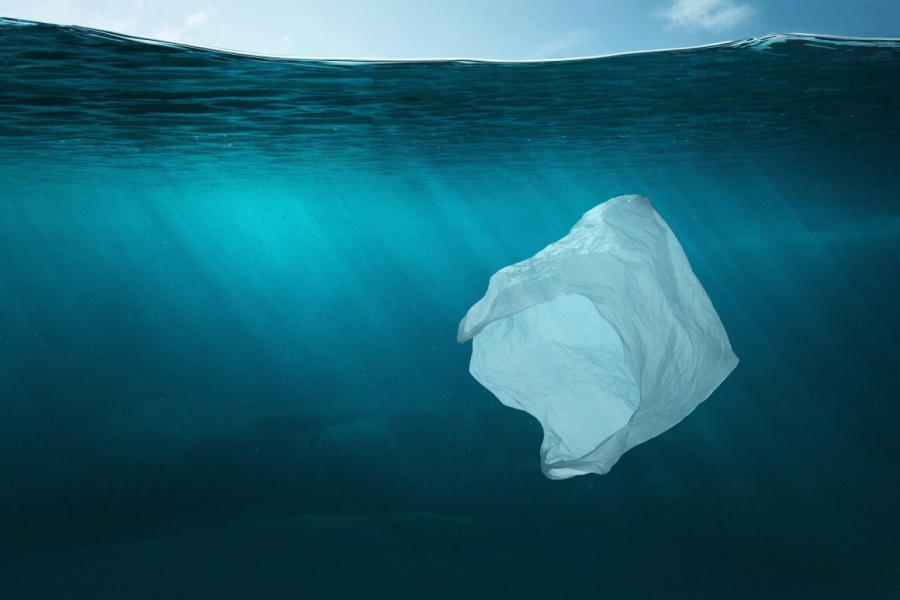 En plastpose flyter under vann i det klare blå havet, som symbol på marin forsøpling og miljøpåvirkningen av plastavfall.
