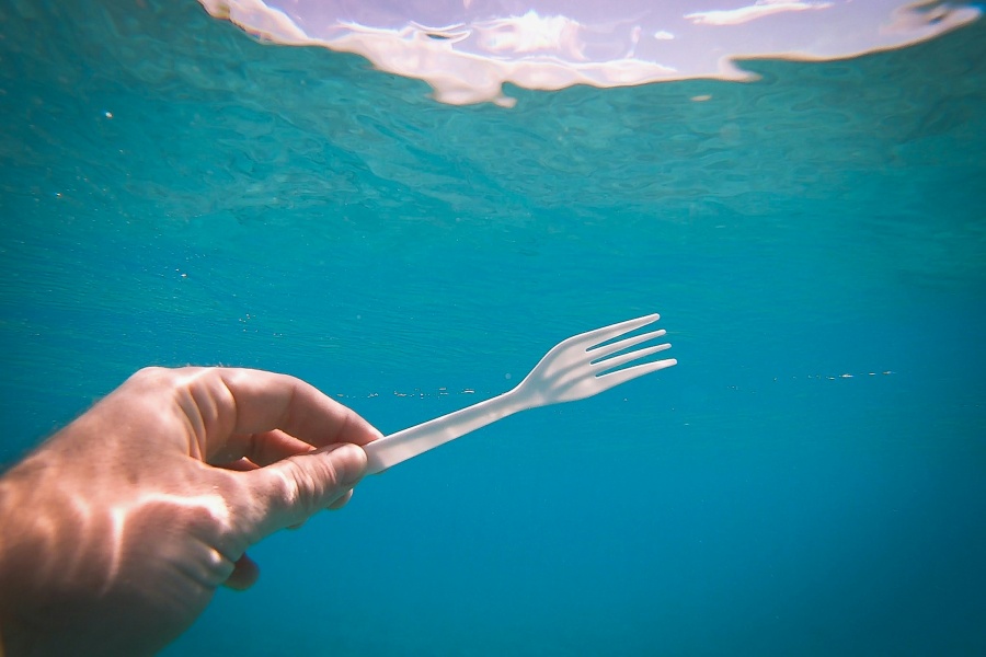 Et undervannsfoto av en hånd som holder en plastikkgaffel.