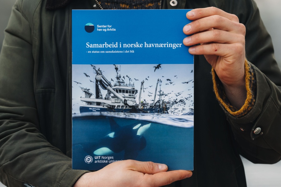 Person holder en rapport med tittelen «Samarbeid i norske havnæringer», med bilde av en fiskebåt over vann og spekkhoggere under vann.