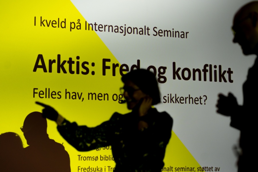 Silhuetter av personer foran en skjerm med teksten «Arktis: Fred og konflikt» under et arrangement hos Internasjonalt Seminar.
