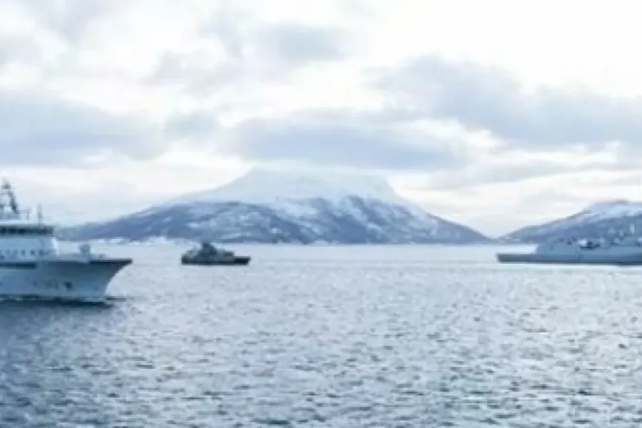 Militærbåter i havet med fjellandskap bak