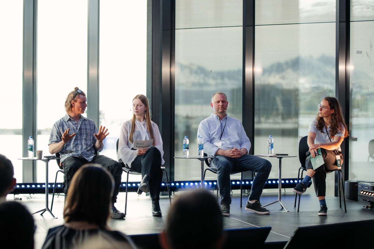 Fire personer sitter i panel under en konferanse, i samtale om grønn omstilling i fiskerinæringen.