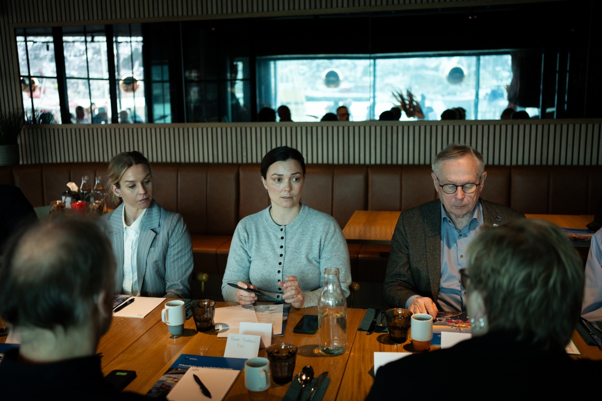 Personer sitter rundt et bord i møte og diskuterer.