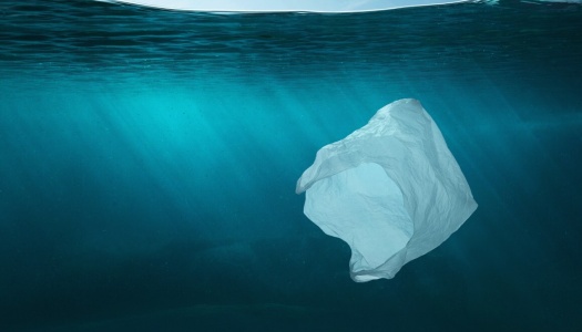 En plastpose flyter under vann i det klare blå havet, som symbol på marin forsøpling og miljøpåvirkningen av plastavfall.