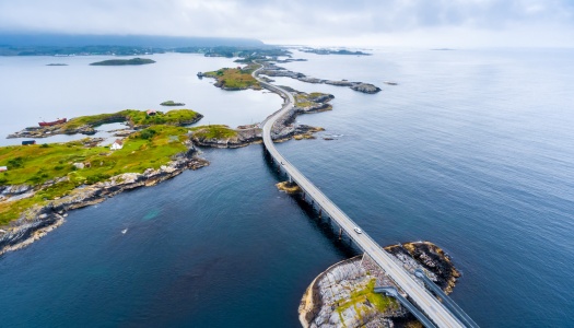 Luftfoto av Atlanterhavsveien som slynger seg over små øyer og broer langs kysten av Møre og Romsdal.