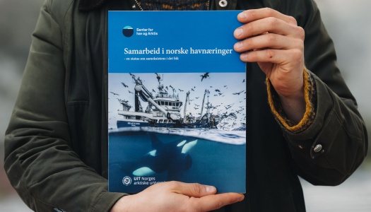 Person holder en rapport med tittelen «Samarbeid i norske havnæringer», med bilde av en fiskebåt over vann og spekkhoggere under vann.