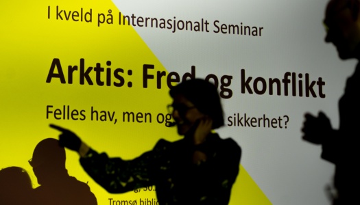 Silhuetter av personer foran en skjerm med teksten «Arktis: Fred og konflikt» under et arrangement hos Internasjonalt Seminar.