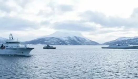 Militærbåter i havet med fjellandskap bak