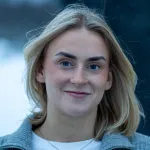 Portrett av en person utendørs i vinterlys, med snø i bakgrunnen.