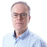 Portrett av mann med briller som ser rett inn i kamera. 