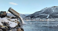 En lastebil tømmer snø i sundet i Tromsø