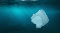 En plastpose flyter under vann i det klare blå havet, som symbol på marin forsøpling og miljøpåvirkningen av plastavfall.
