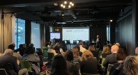 Et konferanserom fylt med deltakere som følger en presentasjon om “Future Svalbard” under Arctic Frontiers, med en taler ved scenen og store vinduer som slipper inn dagslys fra siden.
