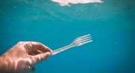 Et undervannsfoto av en hånd som holder en plastikkgaffel.