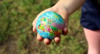 En barnehånd holder en liten jordklode.