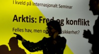 Silhuetter av personer foran en skjerm med teksten «Arktis: Fred og konflikt» under et arrangement hos Internasjonalt Seminar.